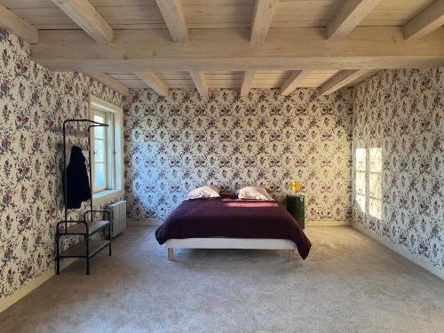 - une chambre avec un lit et du papier peint floral dans l'établissement La Charentaise Dorée, à Juillac-le-Coq