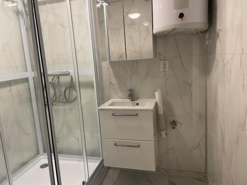 une salle de bain blanche avec lavabo et douche dans l'établissement Quiet and peaceful apartment, close to everything, à Tromsø