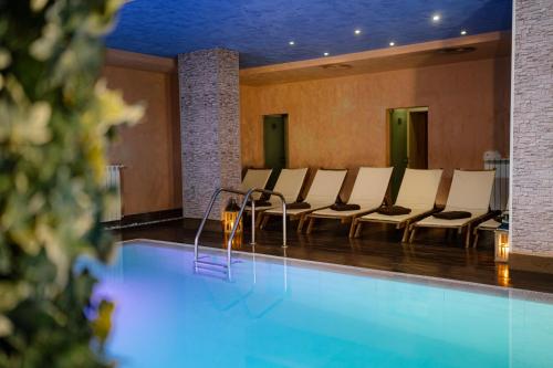 una camera con piscina con sedie di Cornelia Deluxe Residence a Bansko
