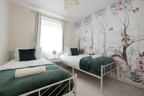 a bedroom with two beds and a mural of trees at 3 Bedroom House in Ebbsfleet in Swanscombe