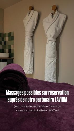 two dresses hanging on a wall in a room at La Maison Gervaiserie & Spa in Réville