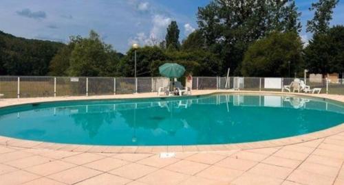 une grande piscine avec un parasol et des chaises dans l'établissement Appartement Résidence avec piscine, à Saint-Geniez-dʼOlt