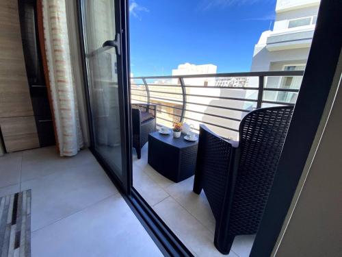 a balcony with two chairs and a table with a view at Cara Flats By Homely in Mellieħa