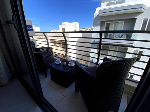 a balcony with chairs and a table and a window at Cara Flats By Homely in Mellieħa