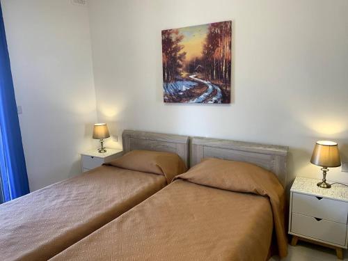 a bedroom with two beds and a painting on the wall at Cara Flats By Homely in Mellieħa