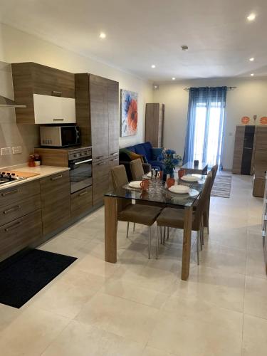 a kitchen and dining room with a table and a kitchen and a couch at Cara Flats By Homely in Mellieħa