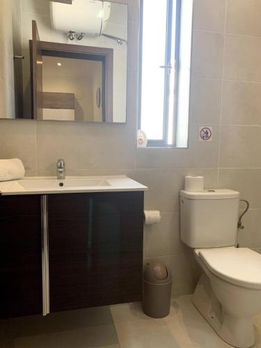 a bathroom with a toilet and a sink and a mirror at Cara Flats By Homely in Mellieħa