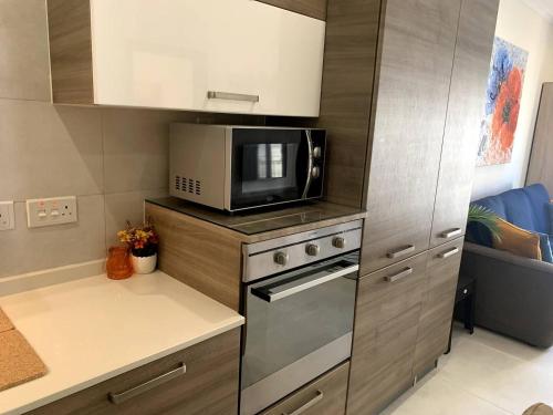 a small kitchen with a microwave and a stove at Cara Flats By Homely in Mellieħa