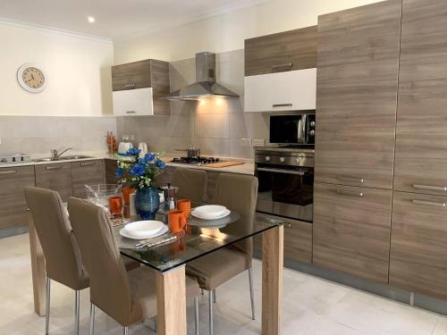a kitchen with a glass table and chairs in a kitchen at Cara Flats By Homely in Mellieħa