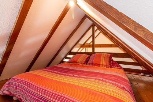 - un lit mansardé avec une couverture rayée colorée dans l'établissement Logement atypique avec mezzanine, à Lingolsheim