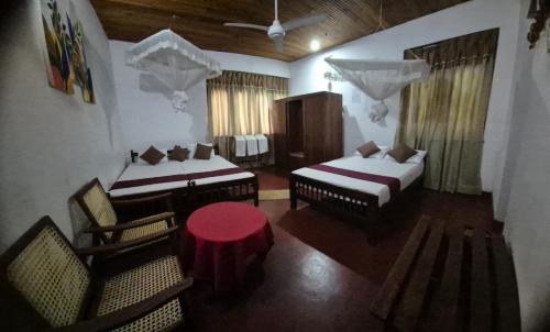 una stanza con due letti, un tavolo e delle sedie di Lazy Bear Best Hostel in Kandy a Kandy