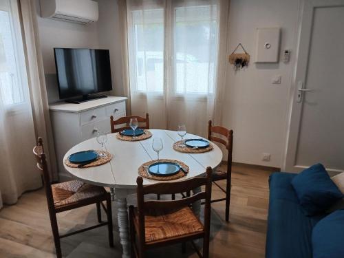 d'une salle à manger avec une table, des chaises et une télévision. dans l'établissement Gîte les Rougets, à Narbonne