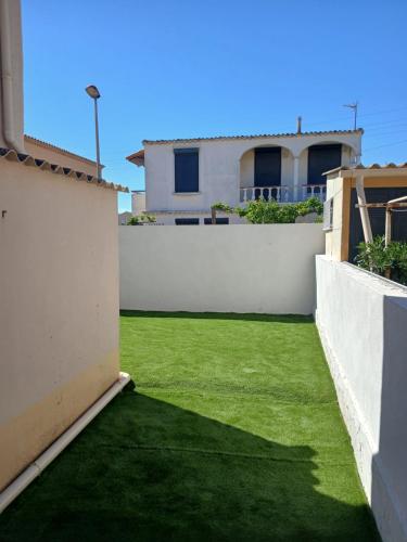 une arrière-cour avec une pelouse verte en face d'une maison dans l'établissement Gîte les Rougets, à Narbonne