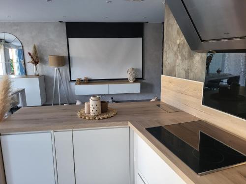 Il comprend une cuisine avec des placards blancs et une télévision murale. dans l'établissement Maison entre mer et montagnes, à La Gaude