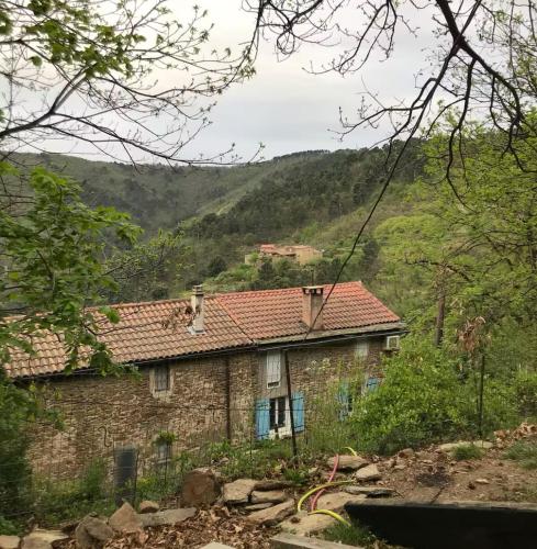 une maison en pierre avec un toit rouge sur une montagne dans l'établissement Petite terrasse en Cévennes, à Peyremale