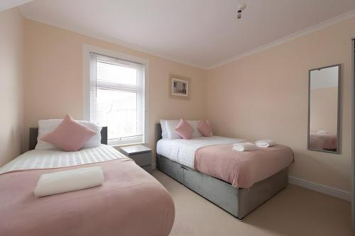 グレーズ・サロックにあるLovely 2 Bed Room House in Graysのベッド2台と鏡のある寝室