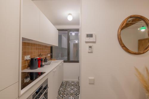 - une cuisine avec des placards blancs et un miroir dans l'établissement Appartement Belle Lettre 2, à Aix-en-Provence