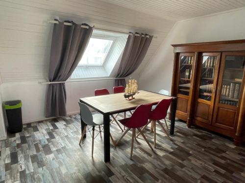 une table à manger avec des chaises rouges et une fenêtre dans l'établissement Appartement Paisible Proche mer, Le Pouldu, à Clohars-Carnoët