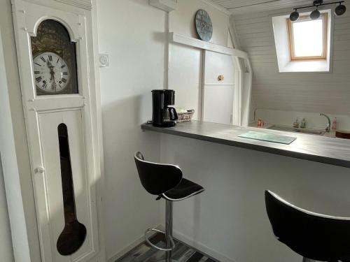 une cuisine avec un comptoir et une horloge au mur dans l'établissement Appartement Paisible Proche mer, Le Pouldu, à Clohars-Carnoët