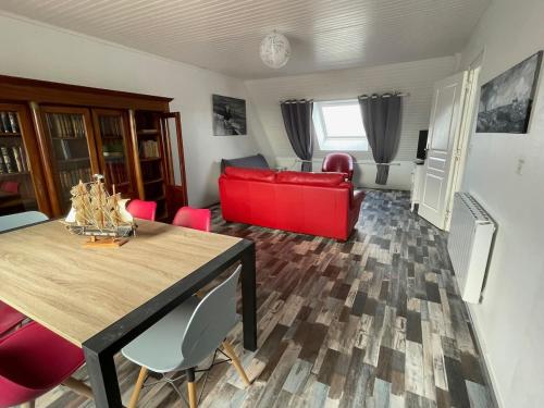 un salon avec un canapé rouge et une table dans l'établissement Appartement Paisible Proche mer, Le Pouldu, à Clohars-Carnoët