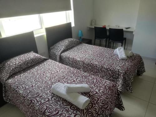 two beds in a hotel room with towels on them at 8villa in St Julian's