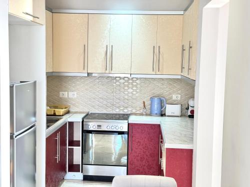 a kitchen with red cabinets and a stove top oven at Amazing Sea View Apartment in Sarandë