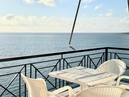 a white table and chairs on a balcony overlooking the ocean at Amazing Sea View Apartment in Sarandë