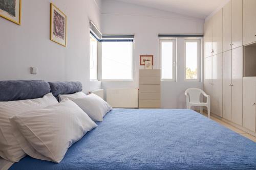 a bedroom with a blue bed with white pillows at Villa Panorama in Makry Gialos