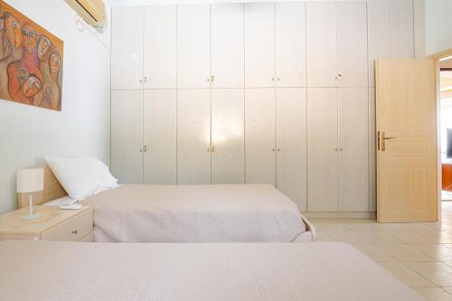 a bedroom with two beds and white cabinets at Villa Panorama in Makry Gialos