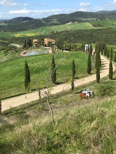 a red truck driving down a dirt road in a field at Agriturismo Villa Felice in Volterra