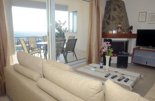 a living room with a couch and a television and a balcony at Villa Panorama in Makry Gialos