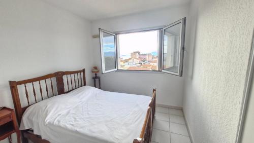 une petite chambre avec un lit et deux fenêtres dans l'établissement Bonna Blanca Appartement à 50 m de la plage , secteur marché - Clim, à Saint Cyprien Plage