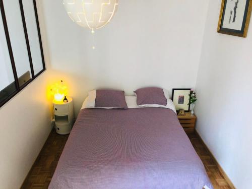Cette chambre comprend un lit avec des draps violets et un lustre. dans l'établissement Beautiful and bright appartement in Montmartre, à Paris