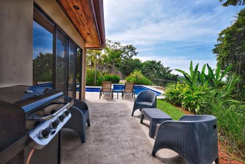 a patio with chairs and a grill and a pool at Villa Romancing The Stone in Ojochal