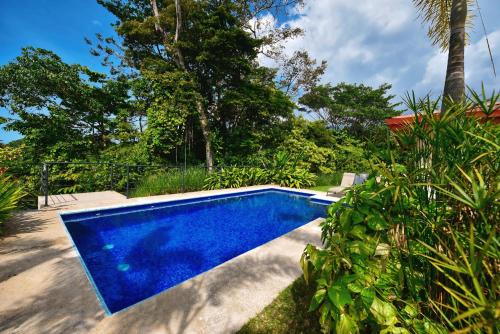 a blue swimming pool in a yard with trees at Villa Romancing The Stone in Ojochal