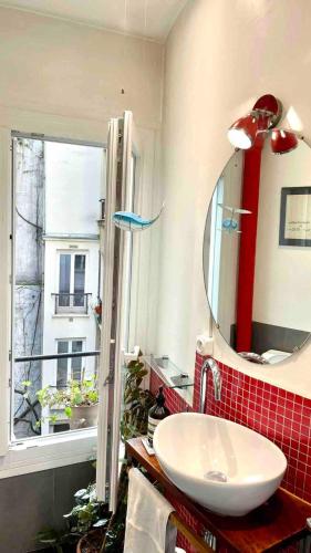 une salle de bain avec un lavabo, un miroir et une fenêtre dans l'établissement Beautiful and bright appartement in Montmartre, à Paris