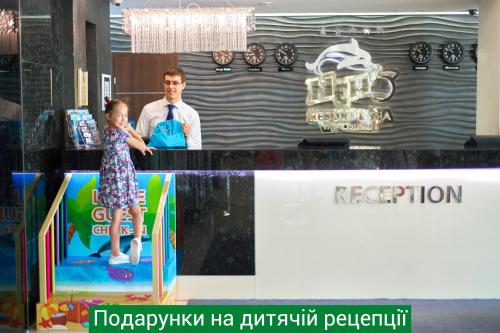 un uomo e una bambina in piedi davanti a un bancone di NEMO Hotel Resort & SPA a Odessa