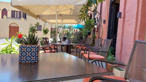 an outdoor patio with tables and chairs and an umbrella at Saint Michel Hotel in Rhodes Town