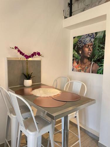 une table à manger avec des chaises blanches et un tableau dans l'établissement studio au port d'Agde proche des plage, au Cap d'Agde
