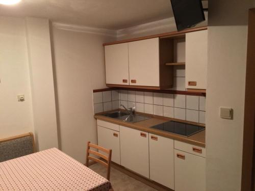 a kitchen with white cabinets and a sink and a table at Fallerhof in Villnoss