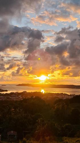 a sunset over a body of water with the sun at Villa verte in Le Robert