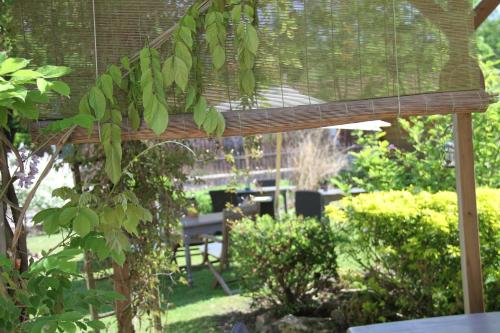 a wooden pergola in a garden with a table at Logis Hôtel De La Chapelle in Milon-la-Chapelle