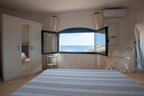 a bedroom with a large window with a view of the ocean at Villa a picco sul mare - Cala Creta in Lampedusa