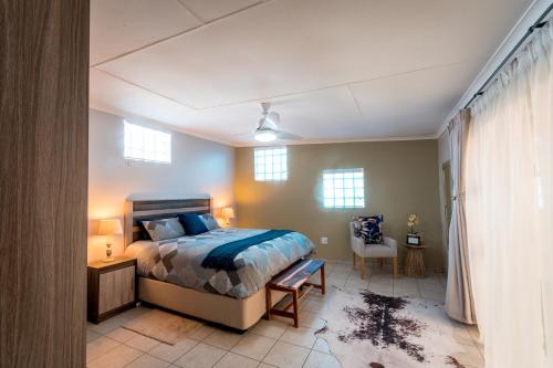 a bedroom with a bed and a table and a chair at Meerkat Manor Self-Catering & Accommodation Windhoek in Windhoek