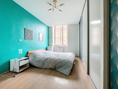 une chambre avec un lit et un mur bleu dans l'établissement La roue libre 3 chambres - 1er étage au centre ville de L'Arbresle, à Éveux