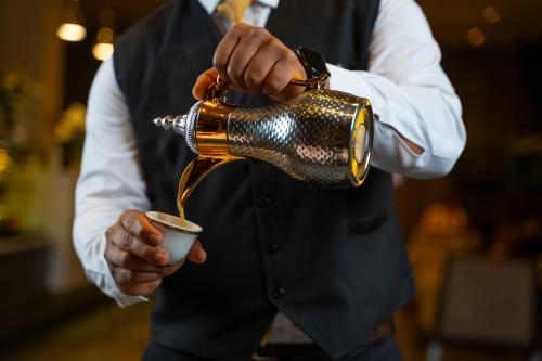 a man is pouring coffee into a cup at Executives Hotel - KAFD in Riyadh