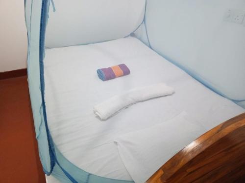 a small bed in a room with a tie on it at Deer Garden Guest in Polonnaruwa