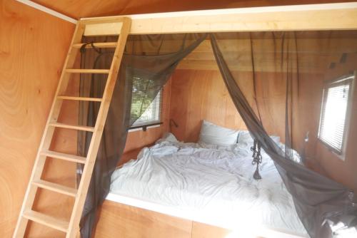 a bedroom with a bunk bed and a ladder at Hoeve Zorglust, salonwagen voor 2 personen met extra slaapkamerhuisje voor 2 - 3 kinderen in Koudekerke