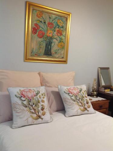 a bed with two pillows and a painting on the wall at The Pink Door in Caledon