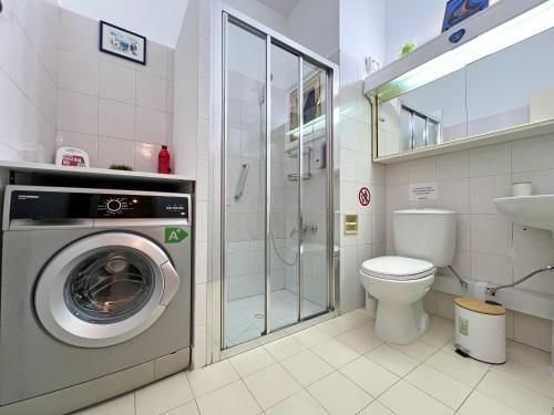 a bathroom with a washing machine and a toilet at Albert's Apartment Mackenzie 001 in Larnaka